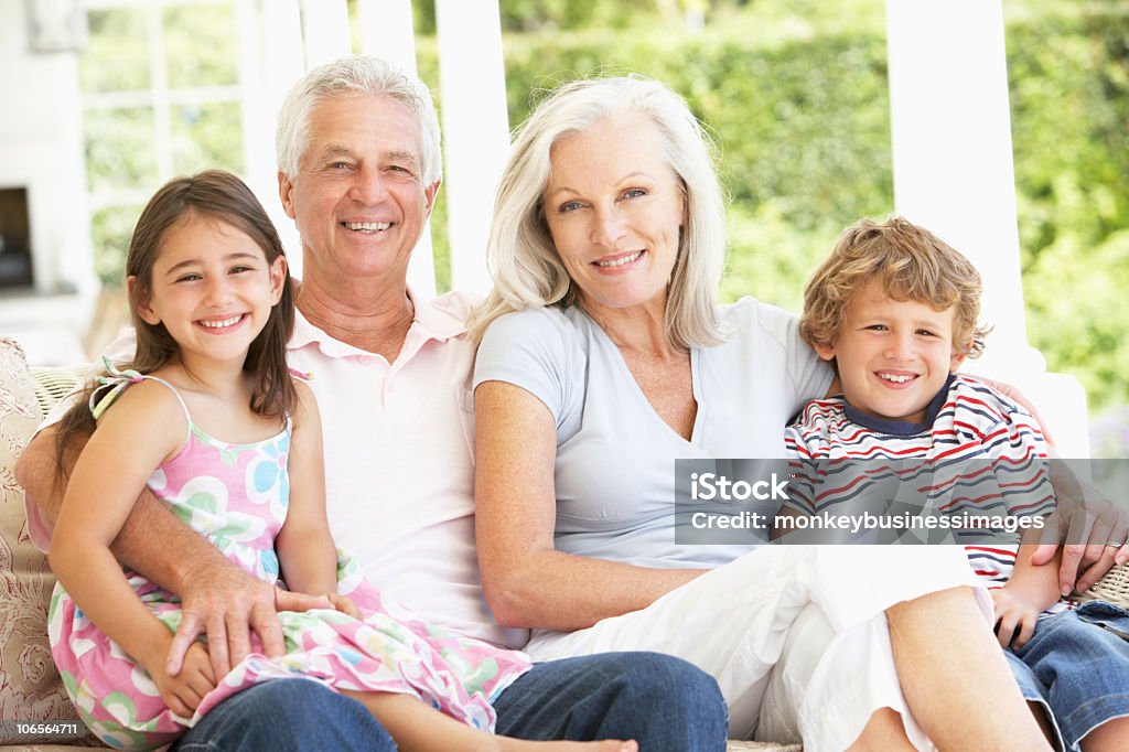 Grands-parents et petits-enfants assis sur un canapé en rotin à la maison - Photo de Famille libre de droits