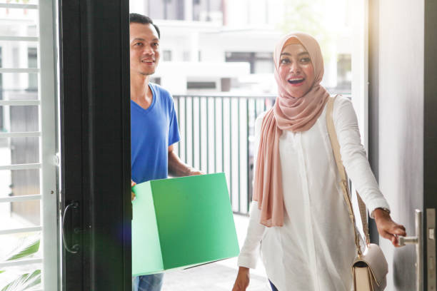 Malay Muslim Couples Moving in to a New Home Couple moving in to new house, carrying a box and looking surprise when opening a door. malay couple stock pictures, royalty-free photos & images