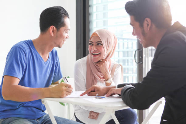 Adult Malay Muslims Signing Documents for House Purchase/ Rental Adult Malay Muslims couple signing documents for house purchase/ rental, sitting in front of a real estate agent. hijab photos stock pictures, royalty-free photos & images
