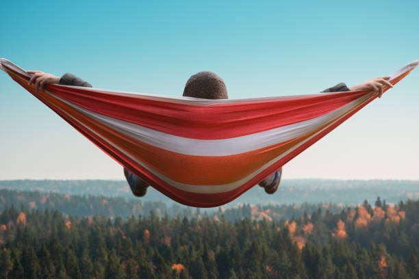 A man sits in a hammock above the forest and enjoys the view. A man sits in a hammock above the forest and enjoys the view norrbotten province stock pictures, royalty-free photos & images