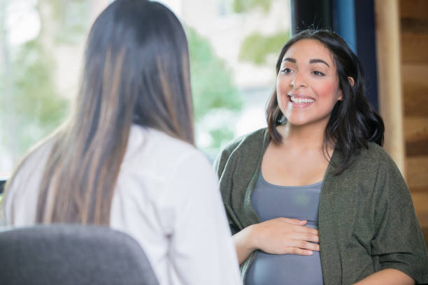 hispanic woman discussing her pregnancy with midwife - look for trains” imagens e fotografias de stock