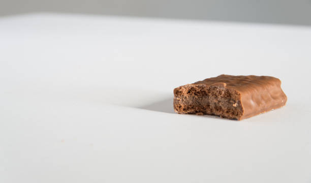 Chocolate biscuit with a bite taken on a white bench