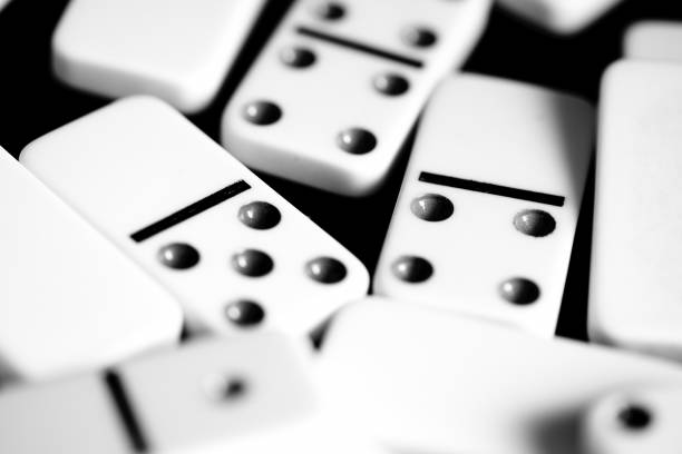 istock Dominoes are scattered on a dark surface close up. Black and white 1065695672