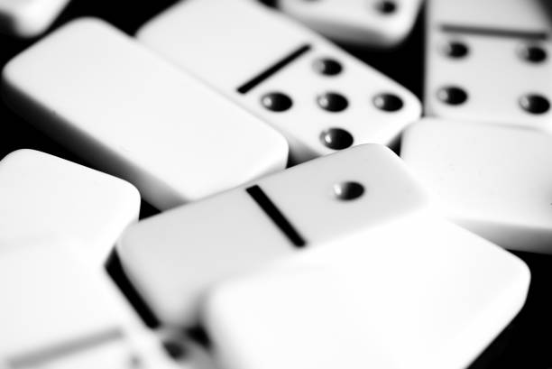 istock Dominoes are scattered on a dark surface close up. Black and white 1065695674