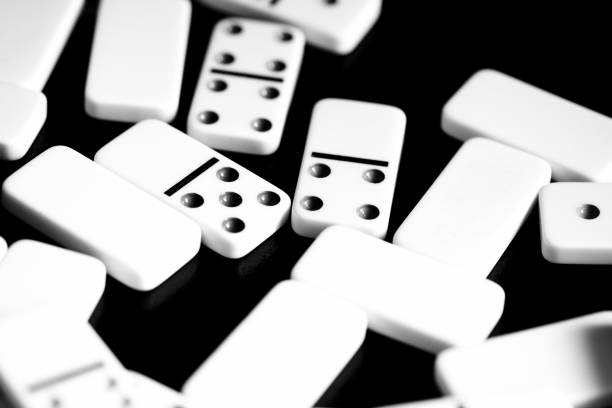 istock Dominoes are scattered on a dark surface close up. Black and white 1065695680