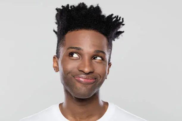 Close up portrait of happy young afro american man looking away on gray background. Young man looking away with a smile on face.