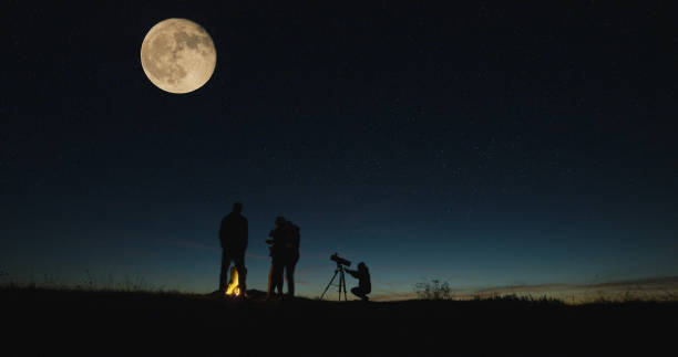 istock Friends with campfire looking on big moon 1065703022