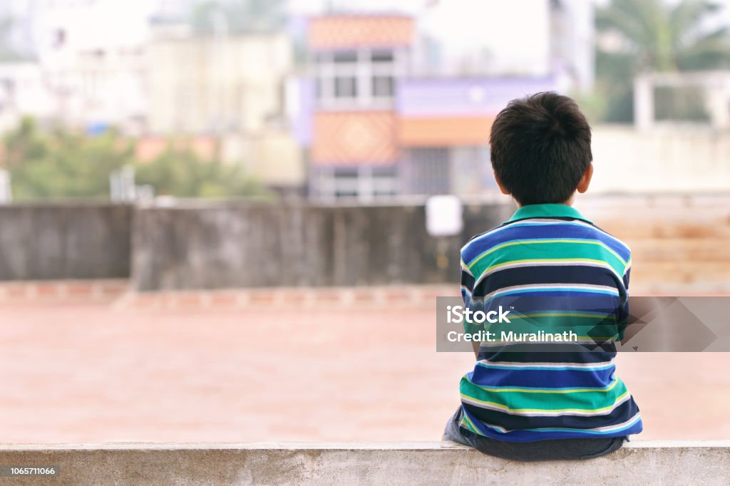 Indian Little Boy Sitting on The Wall Child Stock Photo