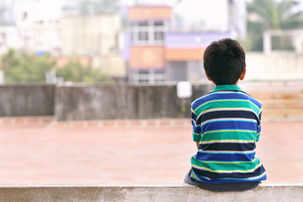 Indian Little Boy Sitting on The Wall stock photo