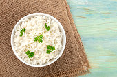 A photo of a bowl of cooked white long rice, shot from the top on rustic textures with copy space