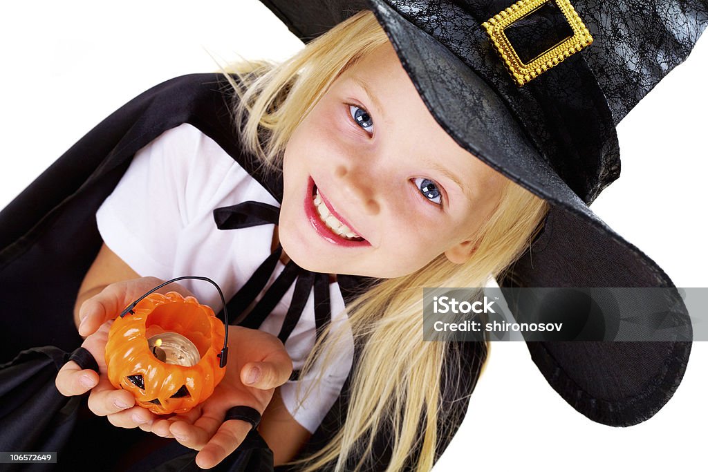 Young girl dresses in a witch's costume Portrait of girl in witch costume and small pumpkin candle in hands Girls Stock Photo