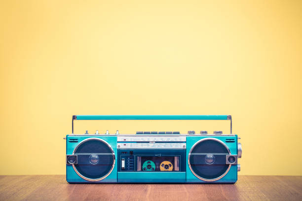Retro outdated portable stereo mint green radio cassette recorder from 80s front yellow background. Vintage old style filtered photo