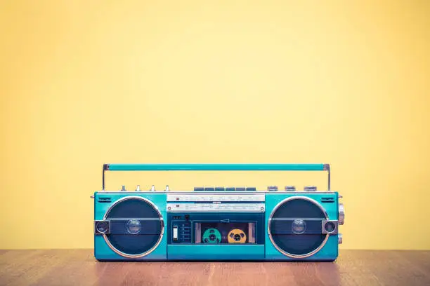 Retro outdated portable stereo mint green radio cassette recorder from 80s front yellow background. Vintage old style filtered photo