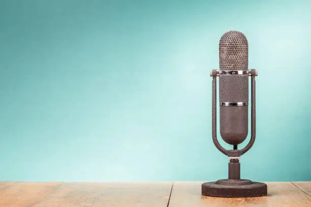 Photo of Retro big microphone from 50s on table front gradient mint green background. Vintage old style filtered photo