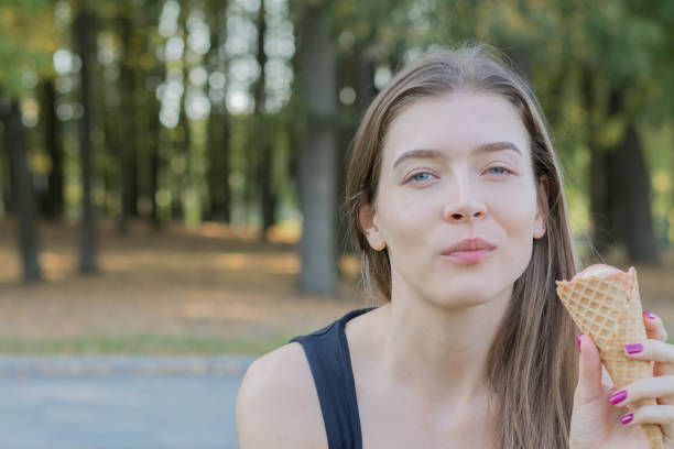 istock Young woman in park eating with ice cream. 1065748480