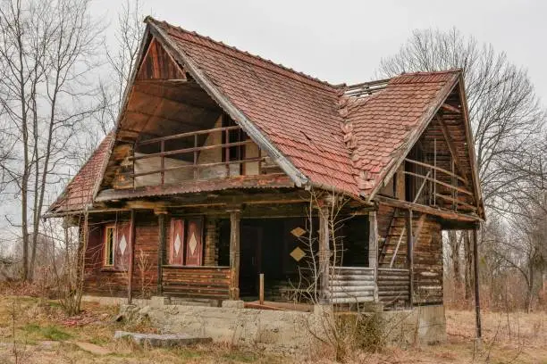 Photo of Old rural abandoned wooden collapsing house against cloudy sky in autumn season