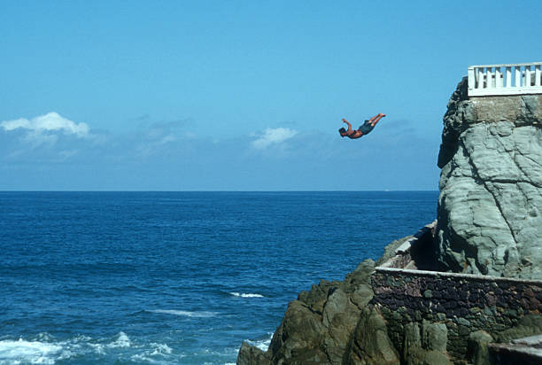 Cliff diver jumping into the ocean stock photo
