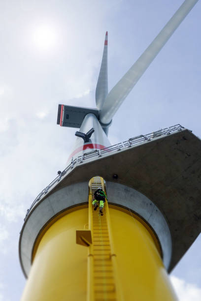 alto lavoratore manuale arrampicata offshore su turbina eolica su scala - offshore wind foto e immagini stock