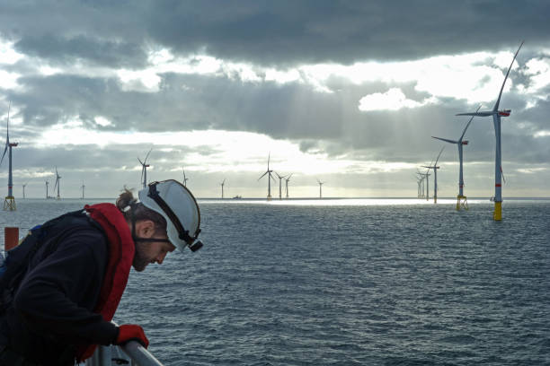 istock Offshore manual worker looking down from wind-turbine with epic background with sunset 1065764696