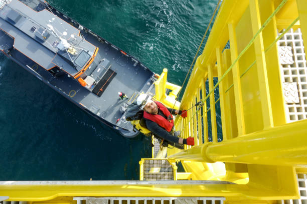 ouvrier haute offshore descendant d’une éolienne sur un navire ladder et transfert en attendant que lui - working windmill photos et images de collection