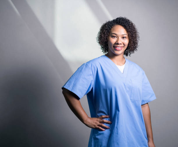 istock Smiling nurse with hand on hip against wall at hospital 1065764936
