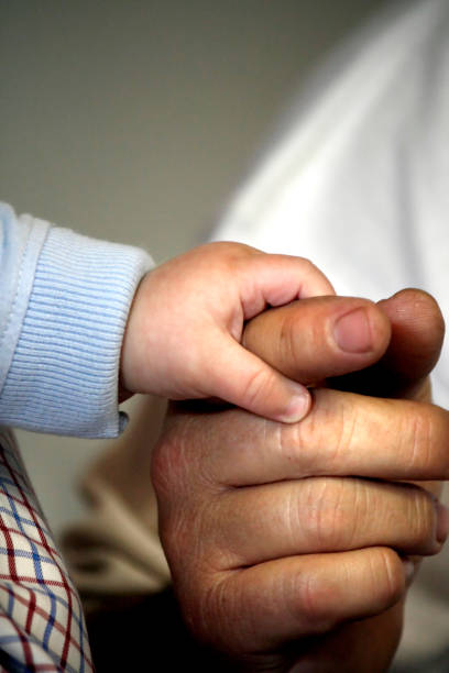istock baby's hand holding the finger 1065766824