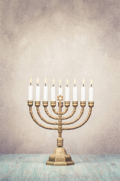 bronce el menorah de hanukkah con velas encendidas sobre fondo de pared vintage antiguo frontal mesa de madera. concepto de tarjeta de felicitación de vacaciones. foto filtrada de estilo retro - menorah hanukkah israel judaism fotografías e imágenes de stock