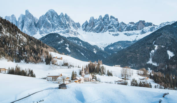 Dolomites mountain peaks with Val di Funes village in winter, South Tyrol, Italy Classic panoramic view of famous Dolomites mountain peaks with the historic village of Val di Funes on a scenic day in winter, South Tyrol, Italy alto adige italy stock pictures, royalty-free photos & images