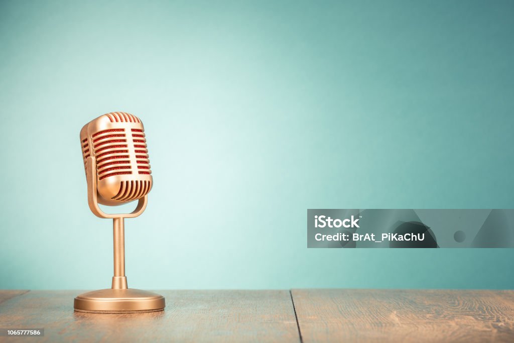 Retro golden microphone for press conference or interview on table front gradient mint green background. Vintage old style filtered photo Microphone Stock Photo