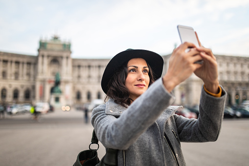 Tourist woman taking selfies in front of public building in Vienna,Austria