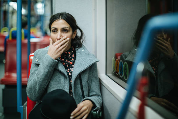 Tired woman in public transportation Woman sitting and yawning in subway , holding hat in hand tired after work stock pictures, royalty-free photos & images