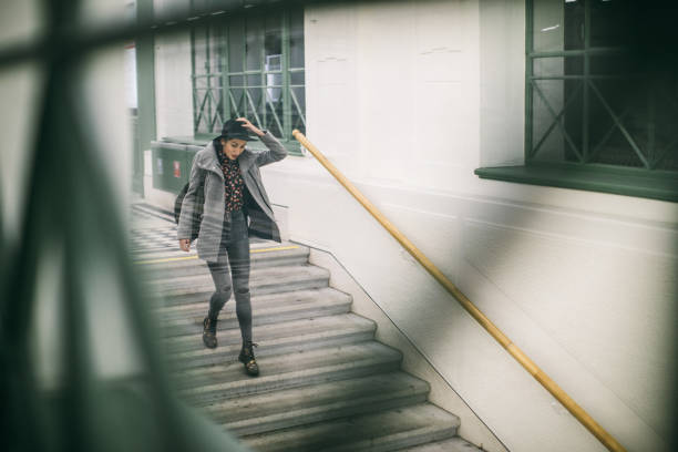 Woman at subway station going down the stairs, holding hat