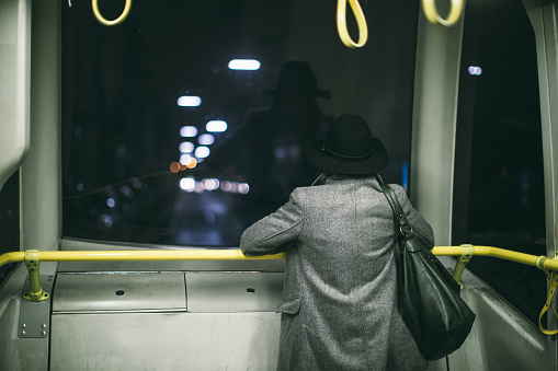 Rear view of woman watching through window in the bus at night