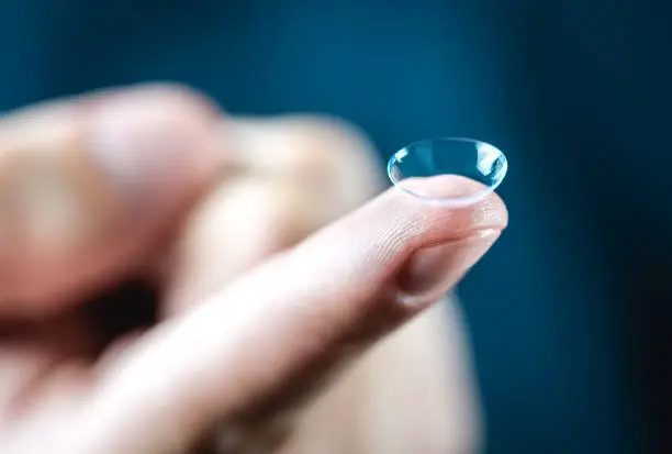 Photo of Contact lenses macro close up. Man holding lens on finger. Customer, patient or eye doctor, oculist or optician in clinic.