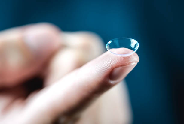 lentes macro close-up. homem segurando a lente no dedo. cliente, médico paciente ou olho, oftalmologista ou oftalmologista na clínica. - cristalino - fotografias e filmes do acervo