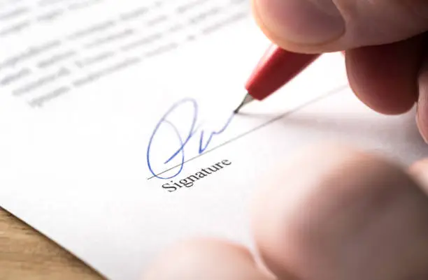 Signing contract, lease or settlement for acquisition, apartment lease, insurance, bank loan, mortgage or business buyout. Man writing name and autograph with pen. The signature is made up. Macro.