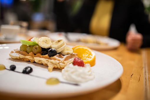 Close up of sweet and delicious waffle with fruit and whipped cream