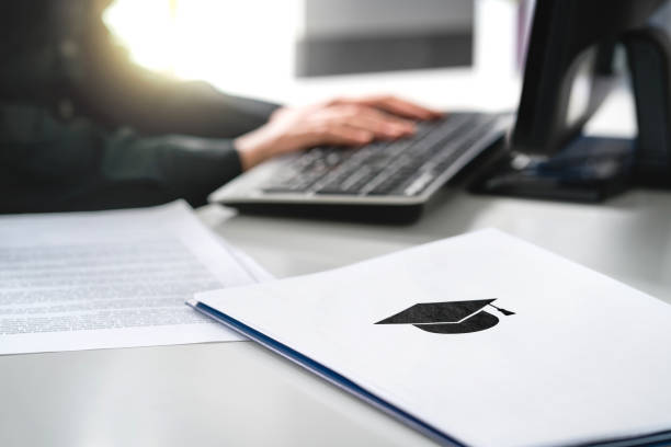 istock Student writing college or university application. Apply to school. Admission or grant. Teacher and computer. Principal or headmaster working in office. 1065782334