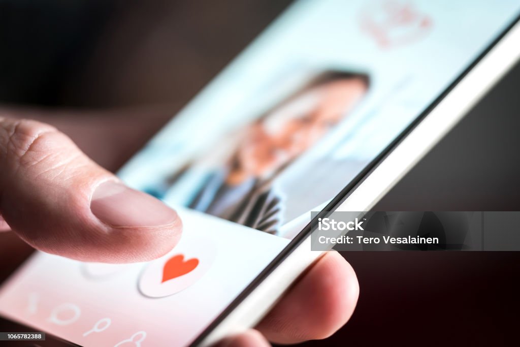Dating app or site in mobile phone screen. Man swiping and liking profiles on relationship site or application. Single guy using smartphone to find love, partner and girlfriend. Dating app or site in mobile phone screen. Man swiping and liking profiles on relationship site or application. Single guy using smartphone to find love, partner and girlfriend. Mockup website. Dating Stock Photo