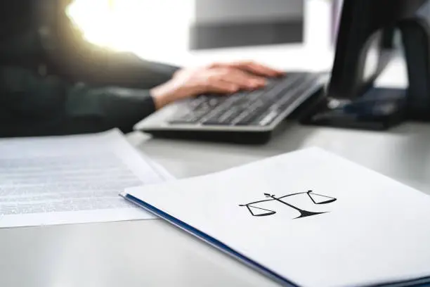 Photo of Attorney with computer. Lawyer working in law firm and company. Solicitor or jurist doing paperwork. Professional business woman writing her will or legal document.