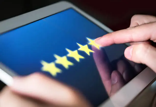 Photo of 5 star rating or review in survey, poll, questionnaire or customer satisfaction research. Happy man giving positive feedback with tablet. Successful business with good reputation.