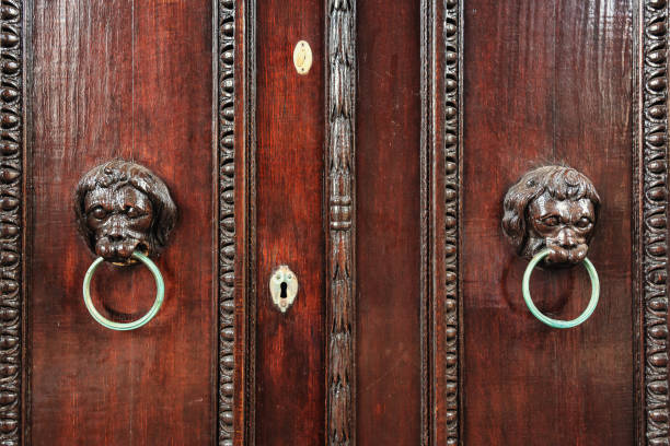 two wood carved lion heads with metal ring as door knocker - door knocker door lion luxury imagens e fotografias de stock