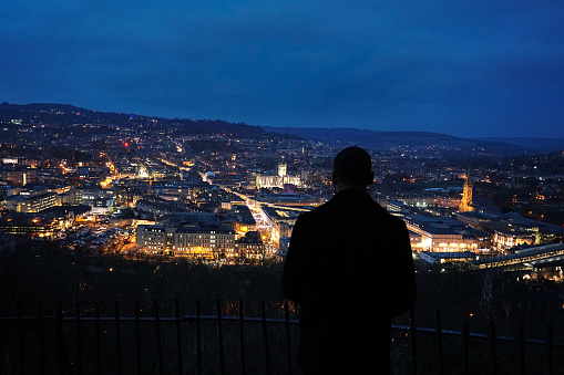 Male Silhouette overlooking the city of Bath, England at night.