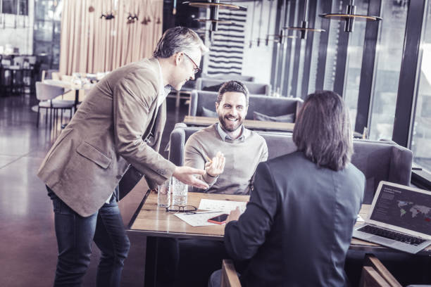 istock Cheerful young man talking to his colleagues 1065789584