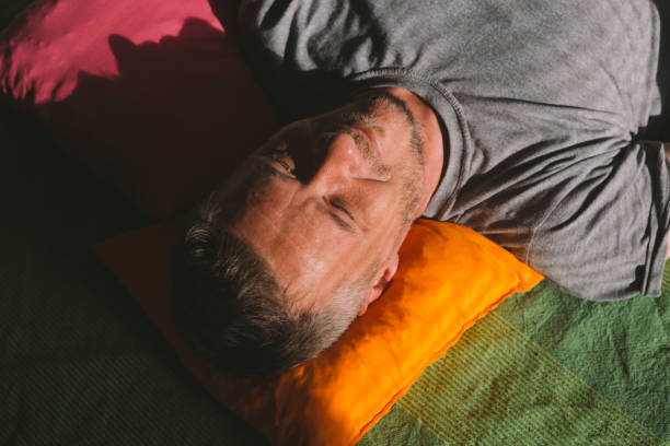 istock Handsome adult man lying down in the bed and day dreaming, illuminated with sunlight through window 1065792994