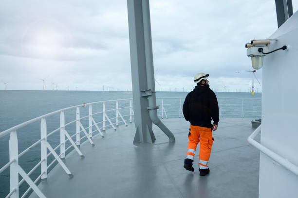 istock Offshore manual worker walking on boat deck with wind-farm front of vessel. 1065795762