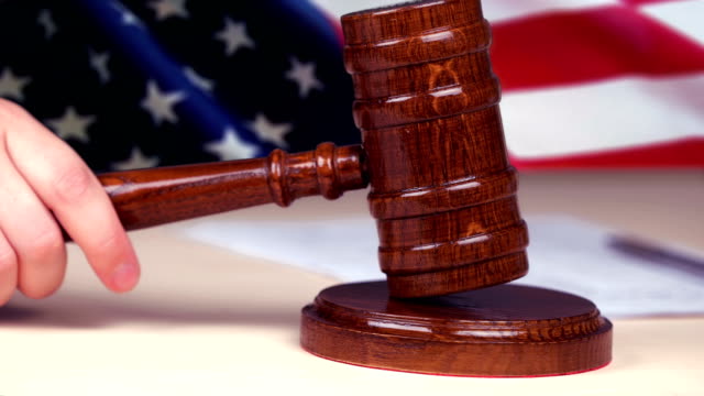 Judge hand striking gavel, US flag on background, american legal system, justice