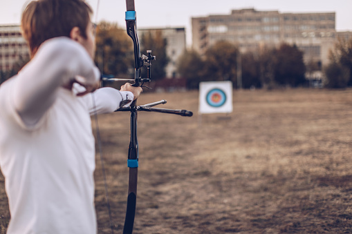 Young man practicing archery outdoors
