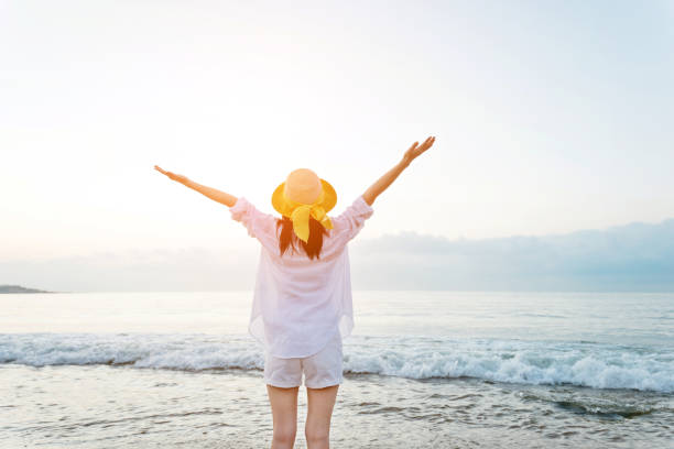 istock Young woman standing on beach with arms raised 1065814052