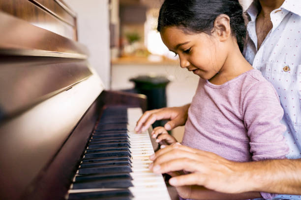 istock Cute girl learning piano with father at home 1065814328
